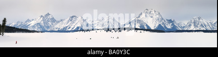 Panorama of Ice fishing on frozen Jackson Lake with Grand Teton peaks and Mount Moran Wyoming USA in winter Stock Photo