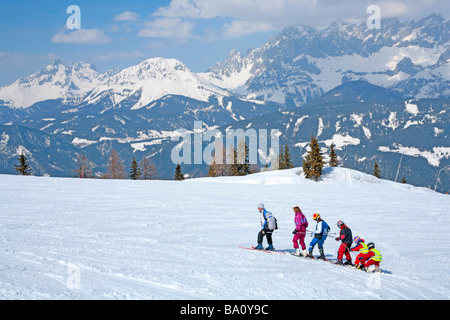 a family Alpine skiing in single file on Reiteralm in Styria, in the background Dachstein Mountain, Austria Stock Photo