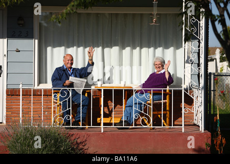 Senior couple waving from front porch Stock Photo
