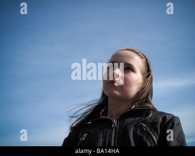 Young girl looking pensively up at blue sky Stock Photo