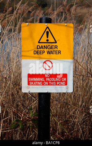 A 'Danger Deep Water' sign post beside a pond in Bedfont Lakes Country Park, Bedfont, Middlesex, UK. Stock Photo