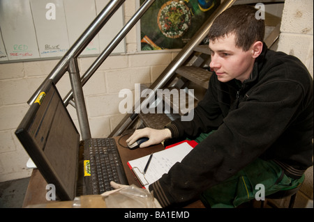 Young man garage worker ordering spare parts for a vehicle using a laptop computer online over the internet, UK Stock Photo