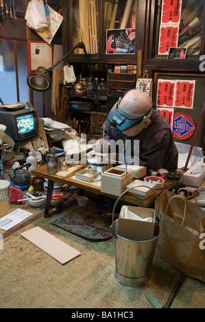 A craftsman hand makes paper lanterns and wooden boxes in an old lantern shop Kyoto Japan Stock Photo