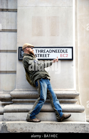 Young male protestor making rude gesture standing below Threadneedle Street EC2 street sign near the Bank of England London Stock Photo