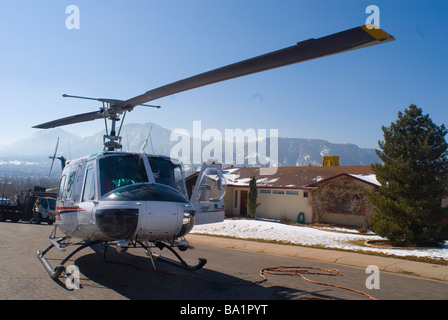 A helicopter lands on a residential street in Boulder Colorado before lifting a new utility pole into place Stock Photo