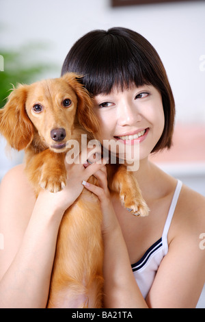 Young woman holding a Dachshund smiling close up Stock Photo