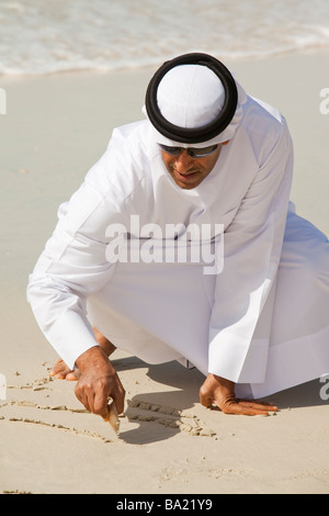 An arab man wearing traditiional dress on a beach in Dubai Stock Photo