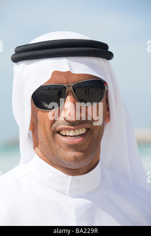 An arab man wearing traditiional dress on a beach in Dubai Stock Photo