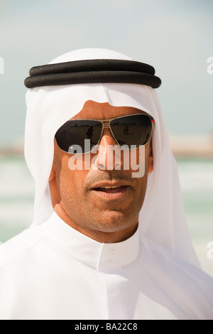 An arab man wearing traditiional dress on a beach in Dubai Stock Photo