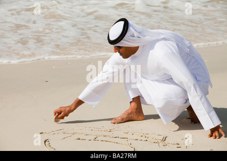 An arab man wearing traditiional dress on a beach in Dubai Stock Photo