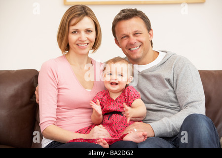Parents And Baby Daughter On Sofa Stock Photo