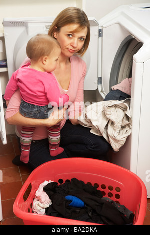 Woman Doing Laundry And Holding Baby Daughter Stock Photo