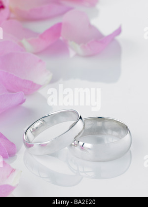 Silver Wedding Rings Resting Next To Flower Petals Stock Photo