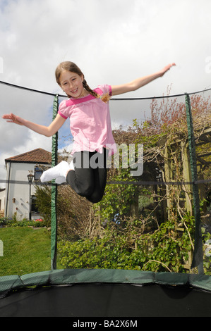 An 8 year old girl bouncing on a trampoline in Cornwall, UK Stock Photo