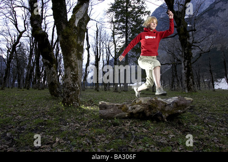 Woman young runs jump log forest series people 20-30 years quite-body blond leisurewear athletically movement runs activity Stock Photo