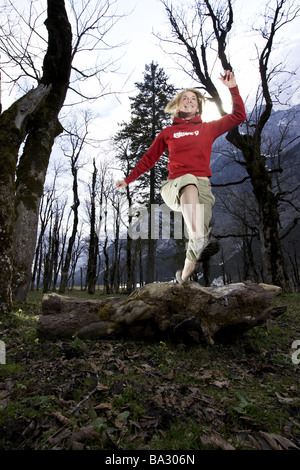 Woman young runs jump log forest series people 20-30 years quite-body blond leisurewear athletically movement runs activity Stock Photo