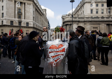 A woman wears a coat with the words 'peaceful and angry' at the G20 protest in London at Bank of England Stock Photo