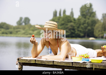 Lies woman young bikini-top sunhat strawberry eats series people 24 years 20-30 years brunette cheerfully smiles fun headgear Stock Photo