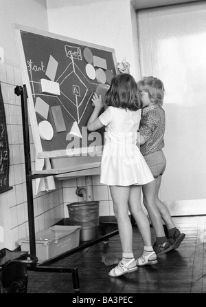 Seventies, black and white photo, edification, school, schoolboys and schoolgirls in a school class during lessons, children aged 7 to 10 years, boy and girl at a blackboard Stock Photo