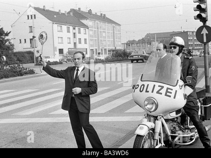 Seventies, black and white photo, traffic, police check, traffic control at a cebra crossing, police officer lifts the signalling disc, beside a policeman on his motorbike, aged 30 to 40 years, D-Bottrop, Ruhr area, North Rhine-Westphalia Stock Photo