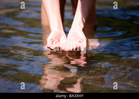 Woman standing in river water in cupped hands Stock Photo
