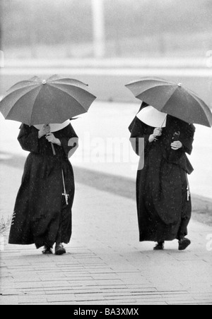 Seventies, black and white photo, weather, rain, two nuns under umbrellas Stock Photo