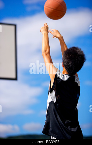 Teenage boy throwing basketball Stock Photo