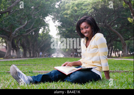 Young Woman Sitting In Park Reading A Book Stock Photo