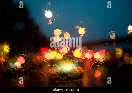 Drivers eye view through a rain covered windscreen of traffic queuing on a rain soaked motorway during the evening rush hour Stock Photo