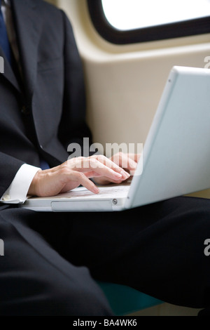 Close up of businessman using laptop on train sitting by window Stock Photo