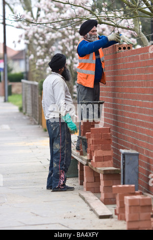 Brick masons constructing a brick wall in Hounslow, London, UK Stock Photo