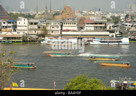 Long tail taxi boats on the Chao Phraya river in Bangkok Thailand with wat pho in the background Stock Photo