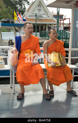 Two Buddhist monks sit on a river taxi in Bangkok Thailand Stock Photo