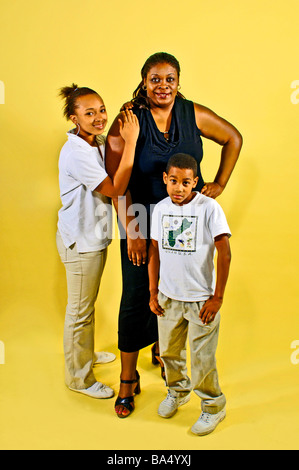 Ethnic single parent, guardian, poses with two child dependents on a bright yellow background Stock Photo
