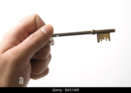 Hand holding an old fashioned key against a white background Stock Photo