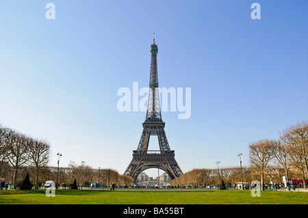 PARIS, France — The Eiffel Tower rises against a clear blue sky on a spring day in the French capital. The iconic wrought-iron lattice structure stands tall over the Champ de Mars, its distinctive silhouette a defining feature of the Parisian skyline. Stock Photo