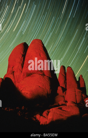 Large granite rocks lit by campfire with star trails whirling in the background at Joshua Tree National Park, California, USA. Stock Photo