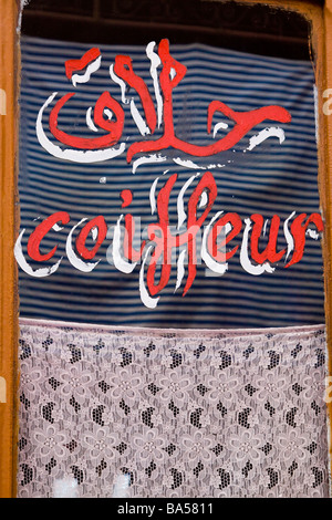 Hand painted sign for a barbers hairdressers shop written in both french and arabic in the Medina, Marrakech Stock Photo