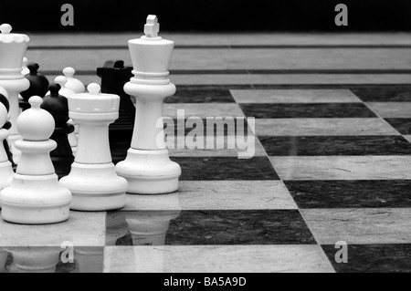 Life size chess pieces and checkered pattern floor tiles. Stock Photo