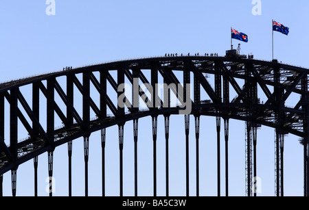 a group of people climbing the Sydney Harbour Bridge with two Australian flags flying Stock Photo
