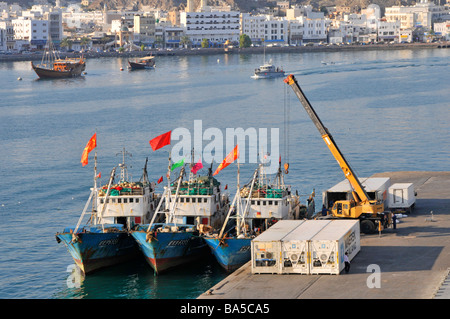 Waterfront and three fishing boats moored at Port Sultan Qaboos at Muttrah also spelt as Mutrah part of Muscat Oman Stock Photo