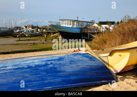 WEST MERSEA, ESSEX, UK - APRIL 05, 2009:   Beached dinghy and houseboat Stock Photo
