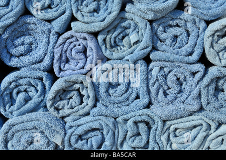 Abstract background end view close up of blue rolled up towel in stacks beside pool awaiting use by cruise ship passengers to place on sun loungers Stock Photo