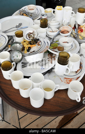 Cruise ship liner close up stack white dirty crockery plates mugs cutlery & left over food cleared up from meal at outdoor buffet table for washing up Stock Photo