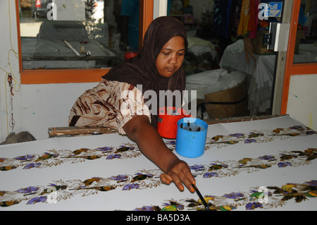 A worker painting traditional patterns at a batik factory on the island of Penang. Stock Photo