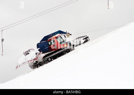 Snowplow on the mountain climbing up with rope. Stock Photo