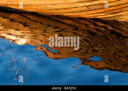 Wooden oar boat reflected in water. Stock Photo