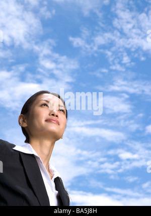Portrait of smiling businesswoman against blue sky Stock Photo