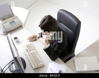 Overhead view of businessman sitting at desk resting chin on hand Stock Photo