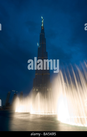 Dubai Fountains illuminated in the evening with the world's tallest skyscraper Burj Khalifa at Dubai Mall in UAE Stock Photo